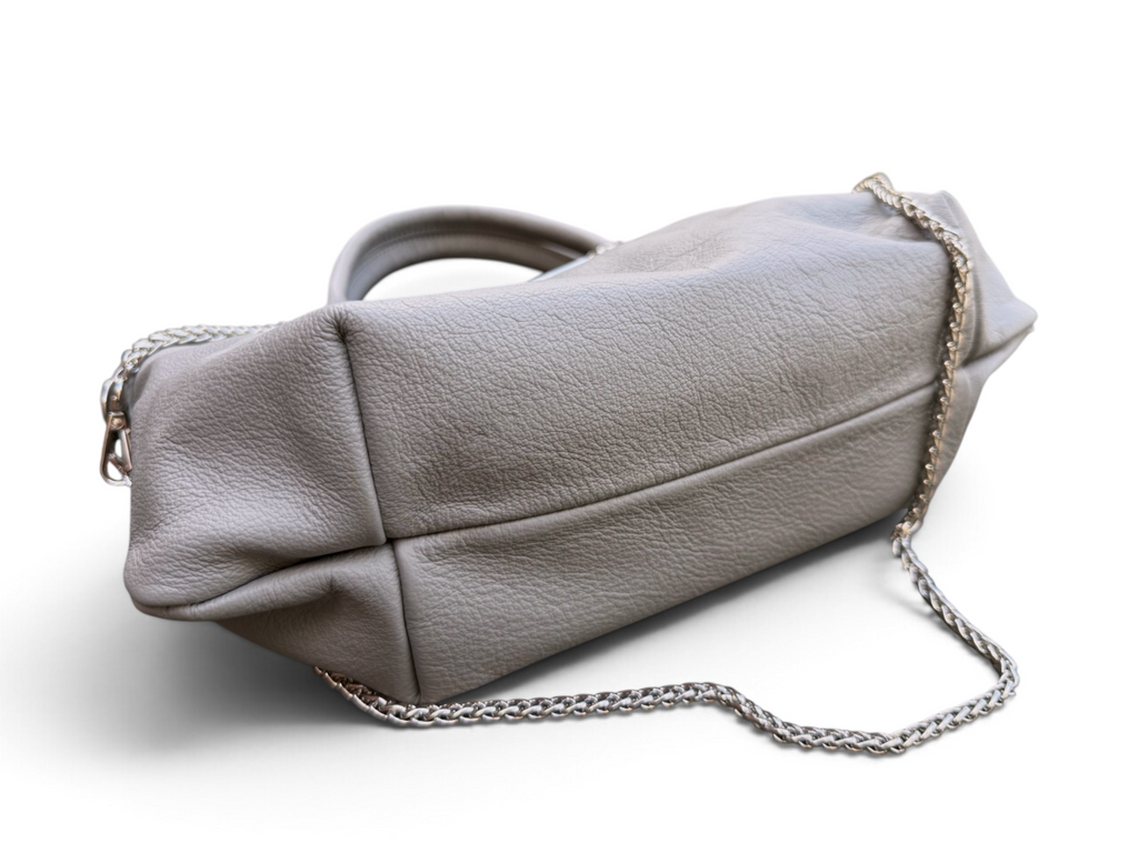 A light gray pebbled leather handbag with a silver-tone chain strap, shown from a bottom angle on a white background.
