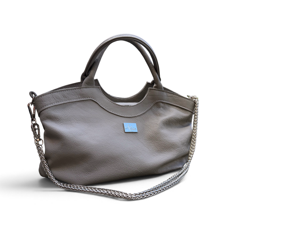 A grey leather handbag with a silver chain strap and a small Lilly & Jude logo badge on the front, shown on a white background.
