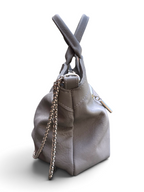 Side view of a grey leather handbag with a twisted top handle and a silver-tone chain strap, shown on a plain white background.