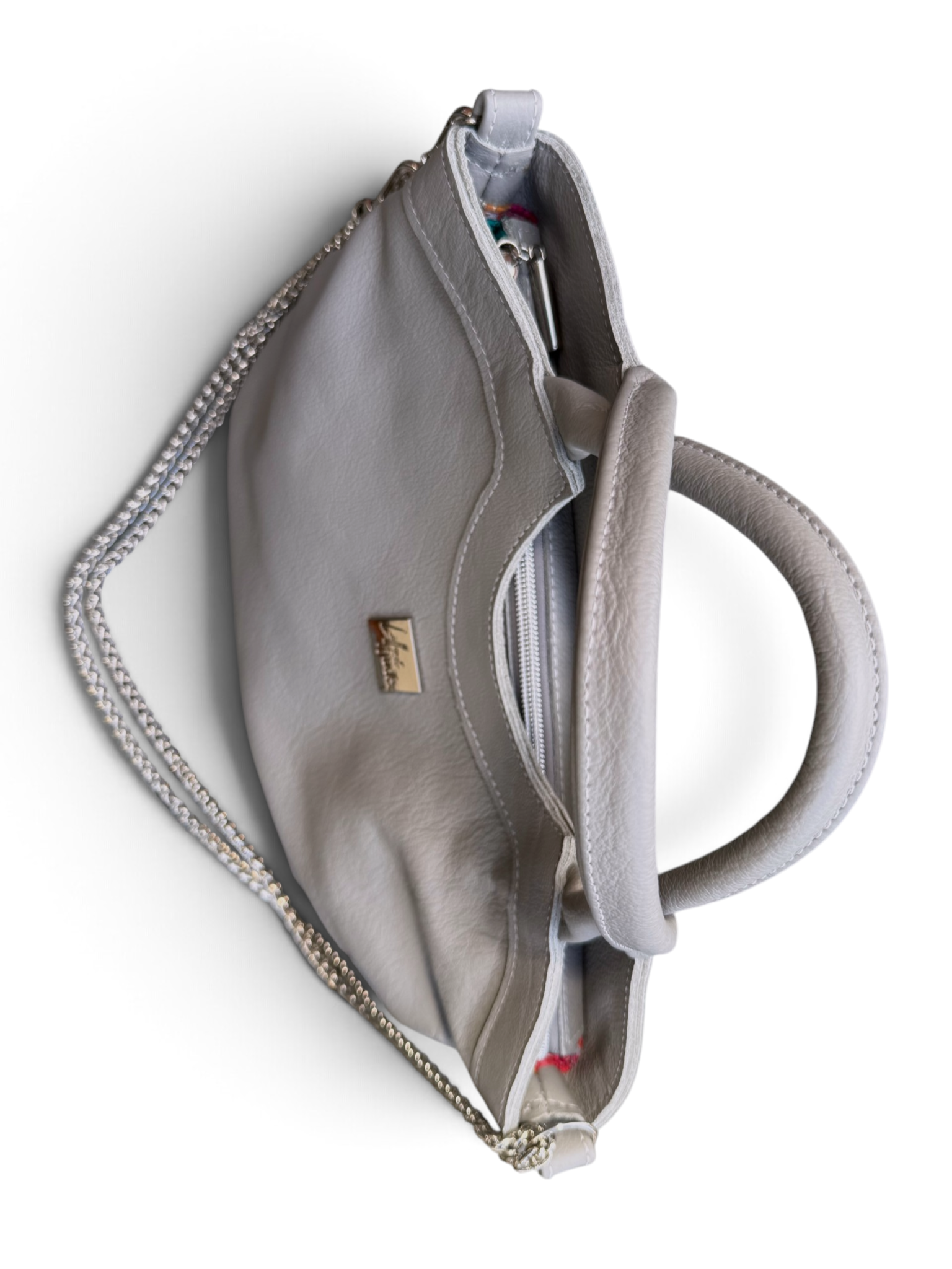 A light grey leather handbag shown from a top-down view, featuring a circular top handle, a zippered main compartment, a side zipper, and a small silver-tone logo plaque on the front.