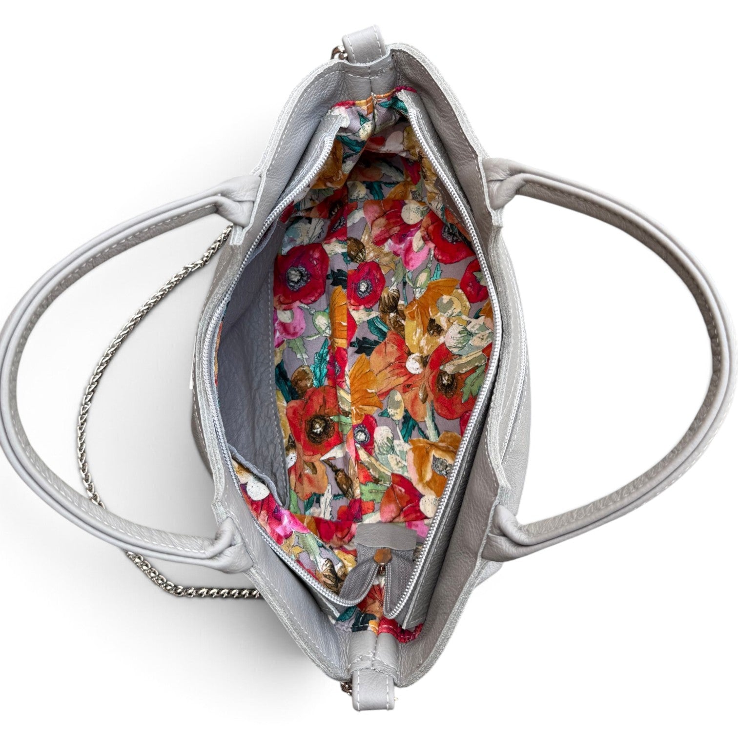 An open silver handbag shown from above, revealing a colorful floral-patterned interior lining with red, orange, pink, and yellow flowers.