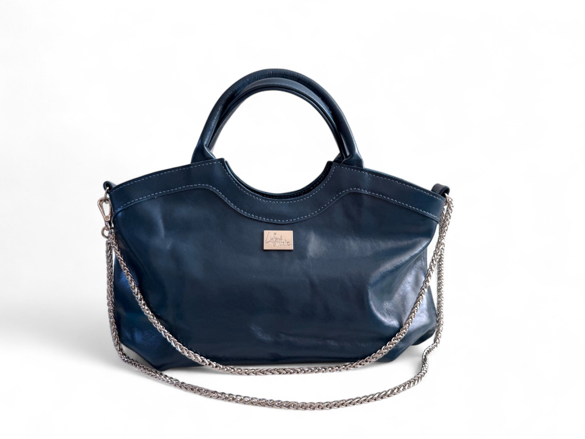 Flossy handbag in genuine navy leather with a silver chain detail on a white background. Sustainable fashion by Lilly & Jude