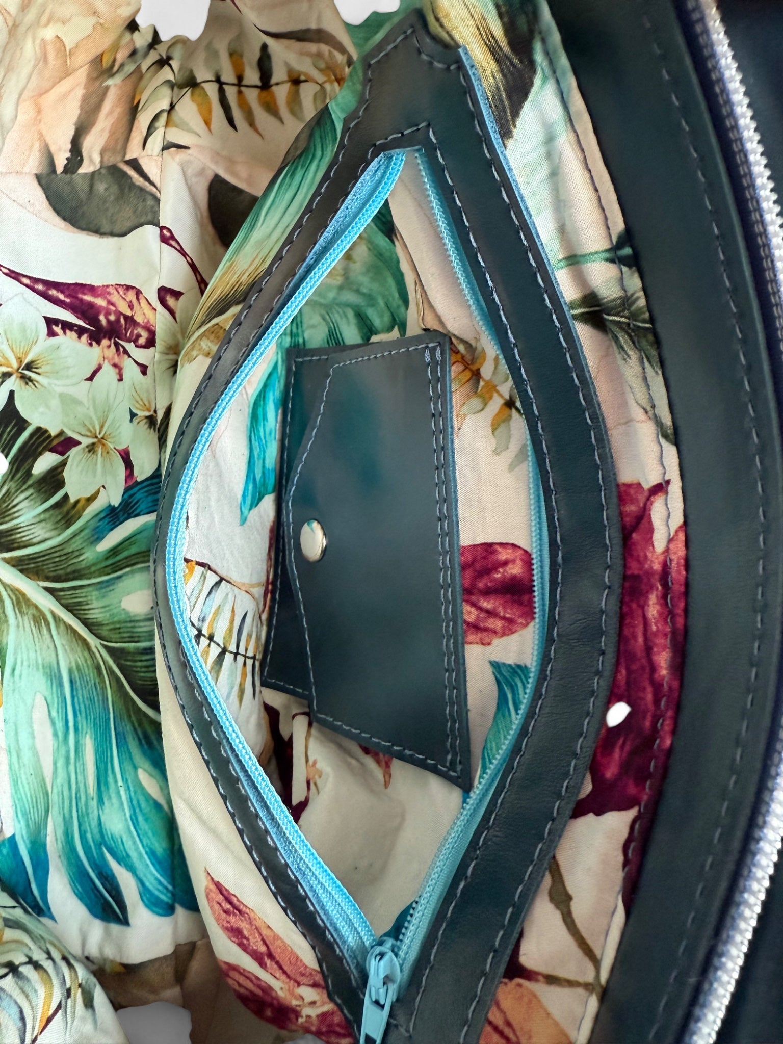 Interior view of the Flossy handbag. The image shows the tropical floral lining and the open interior zipper pocket to show the Lilly & Jude signature integrated purse inside.