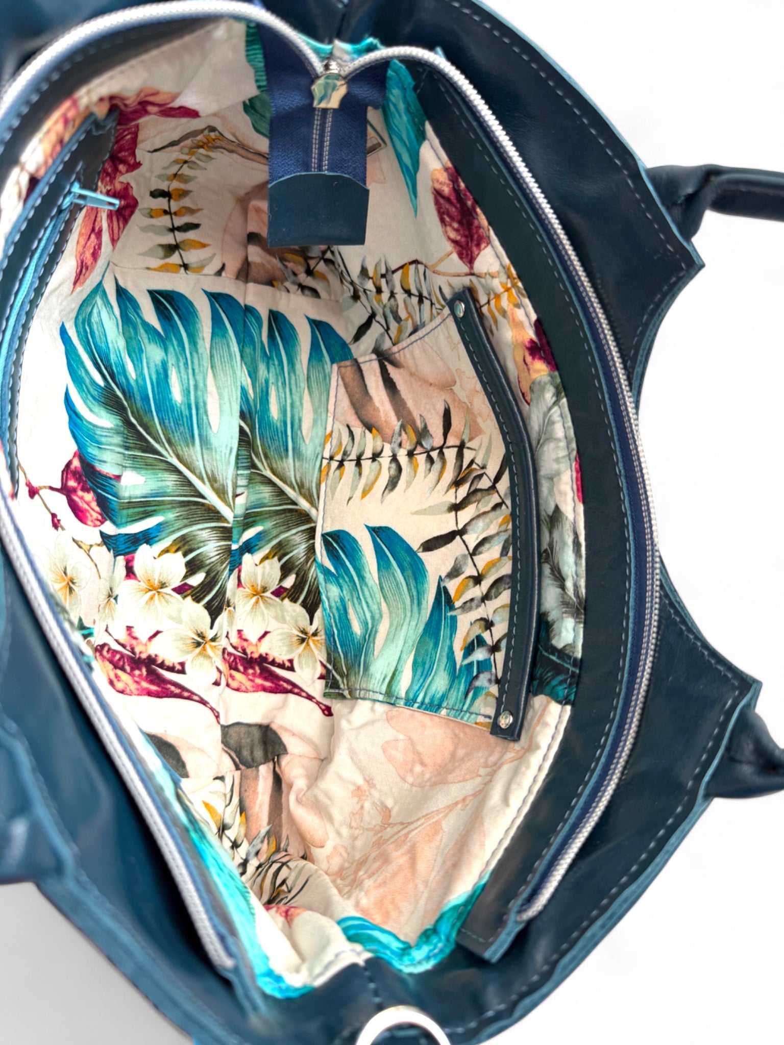 Interior view of the Flossy handbag by Lillly & Jude. The image shows the tropical style interior and highlights the leather trimmed slip pocket