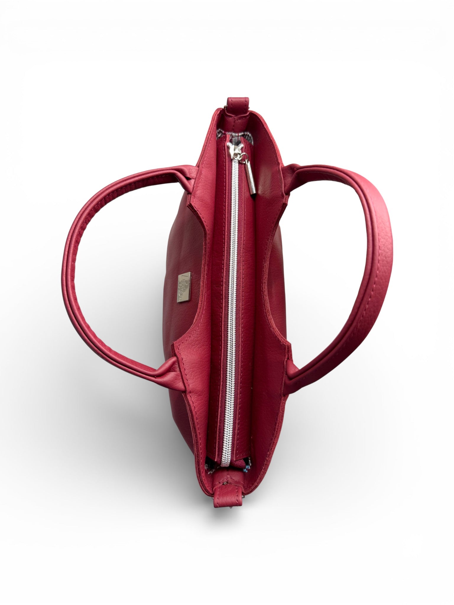 An overhead view of the Flossy handbag with the handles open, to show the zipper opening at the top of the bag. It also shows the visible Lilly & Jude  brand logo on a white background