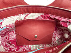 Close-up of  the interior of the Flossy a red leather handbag. The shot highlights the raspberry red and pale blue lining fabric and the Lilly & Jude signature integrated purse / wallet