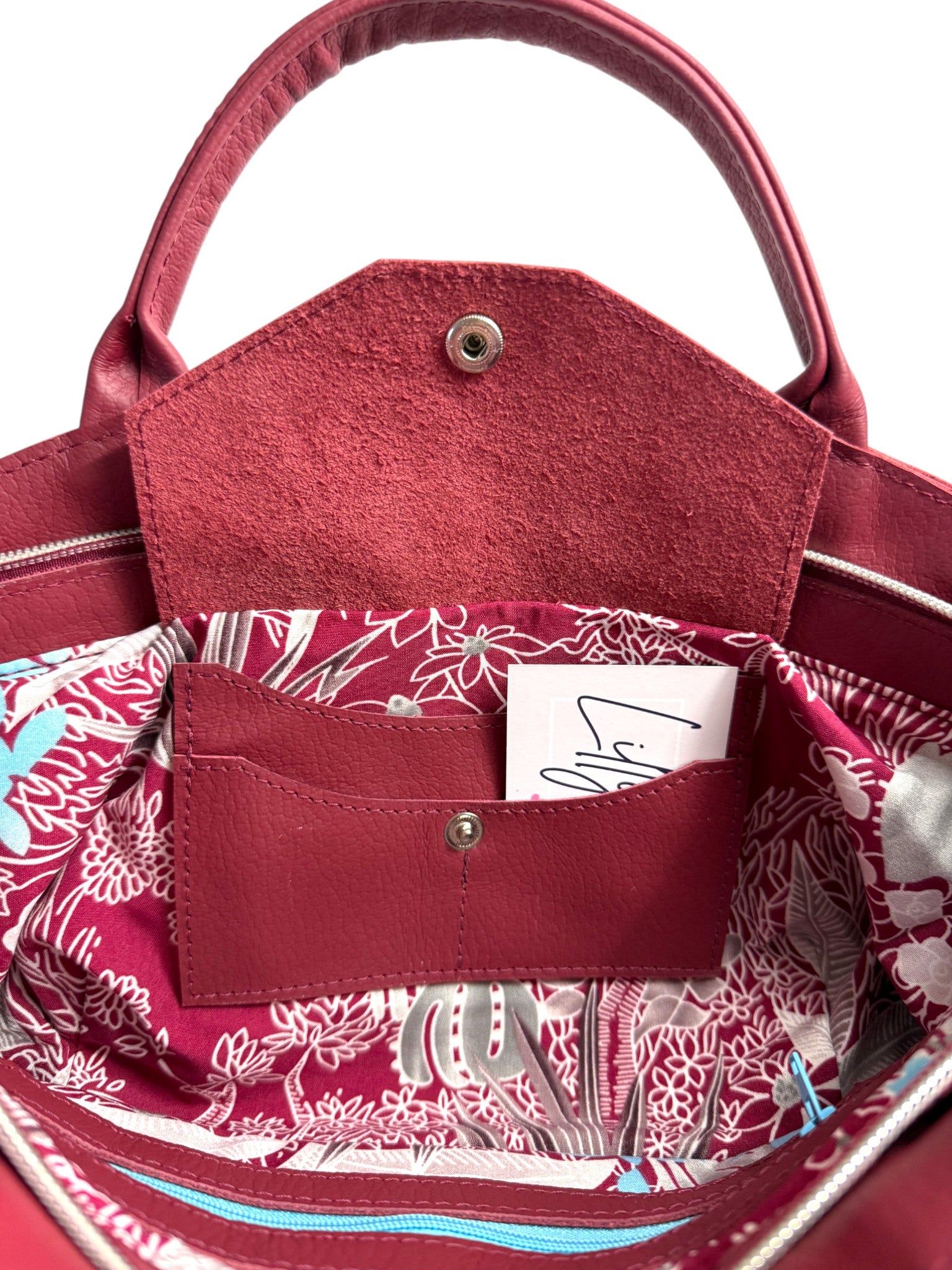 Interior shot of the red genuine, rescued leather Flossy handbag with floral interior and the open integrated purse, highlighting the space for bank cards, cash and coins