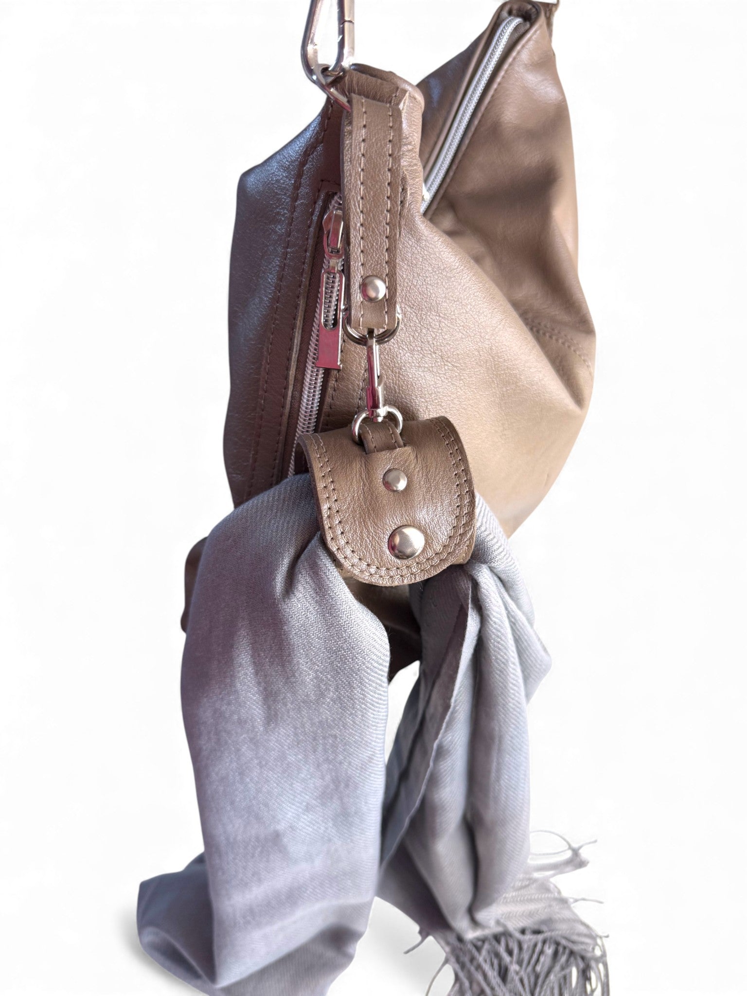Taupe leather bag with an accessory cuff and grey scarf on a white background