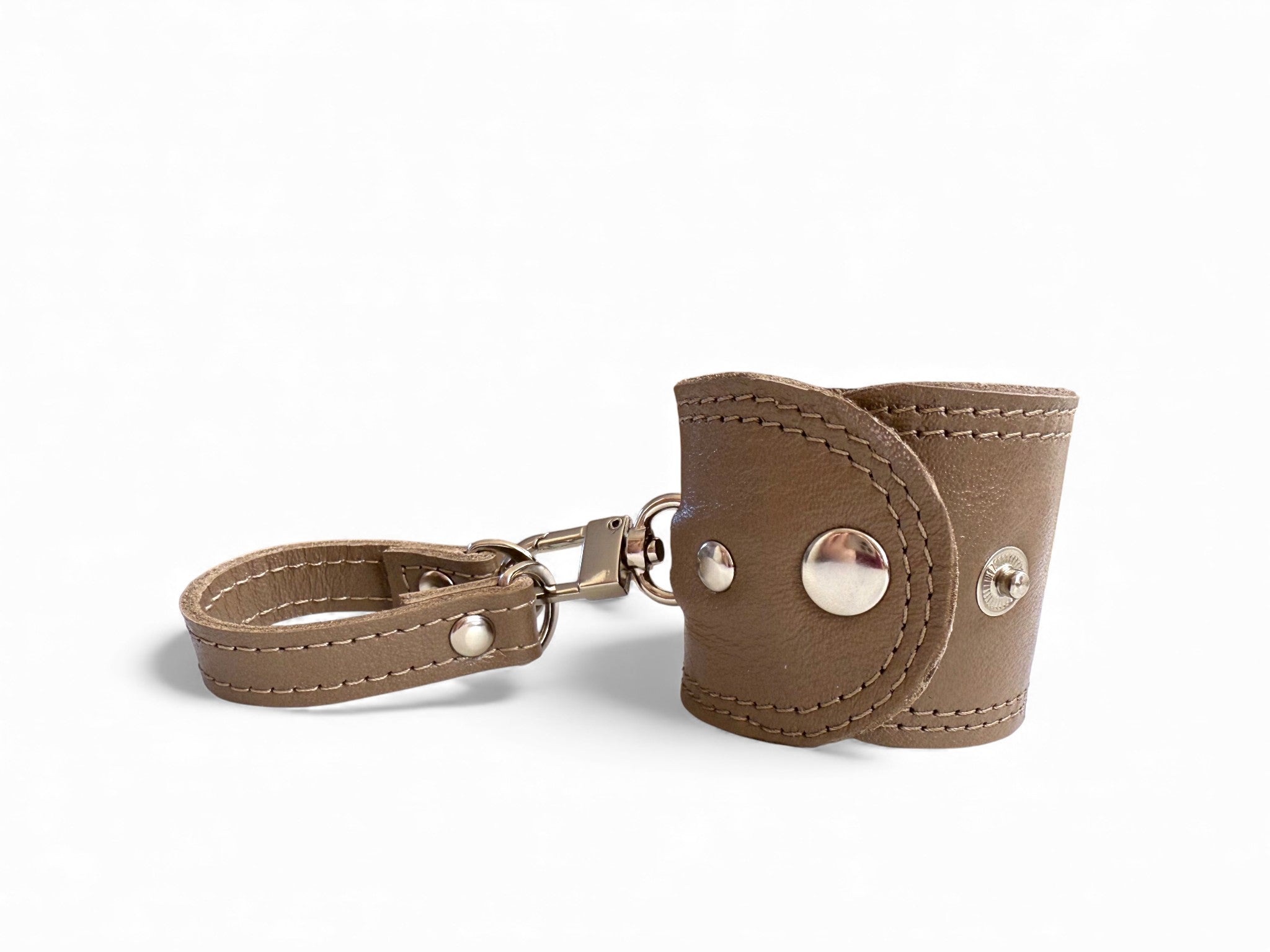 Taupe leather accessory cuff with metal clasps on a white background