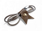 Taupe leather cord keeper with a silver press stud on a white background