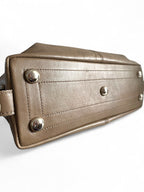 Close-up of a taupe leather bag with silver studs on a white background.