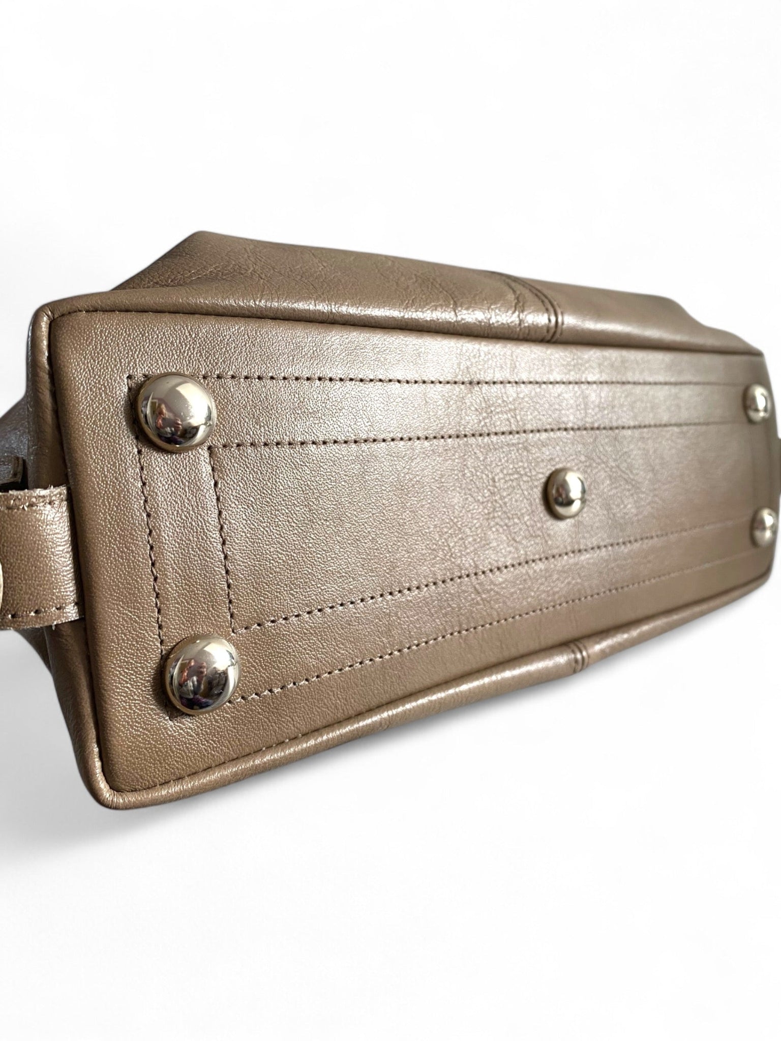 Close-up of a taupe leather bag with silver studs on a white background.
