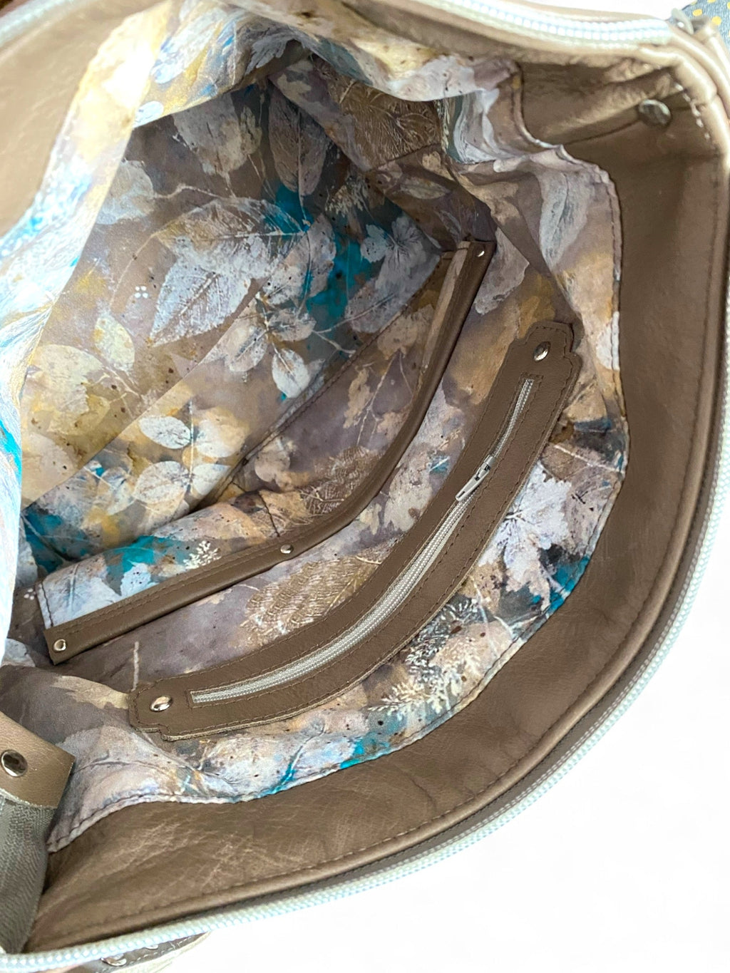 Close-up of a taupe leather bag's interior with floral patterned lining.