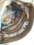 Close-up of a taupe leather bag's interior with floral patterned lining.