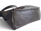 A dark grey textured leather handbag lying down, showing the bottom, on a white background.