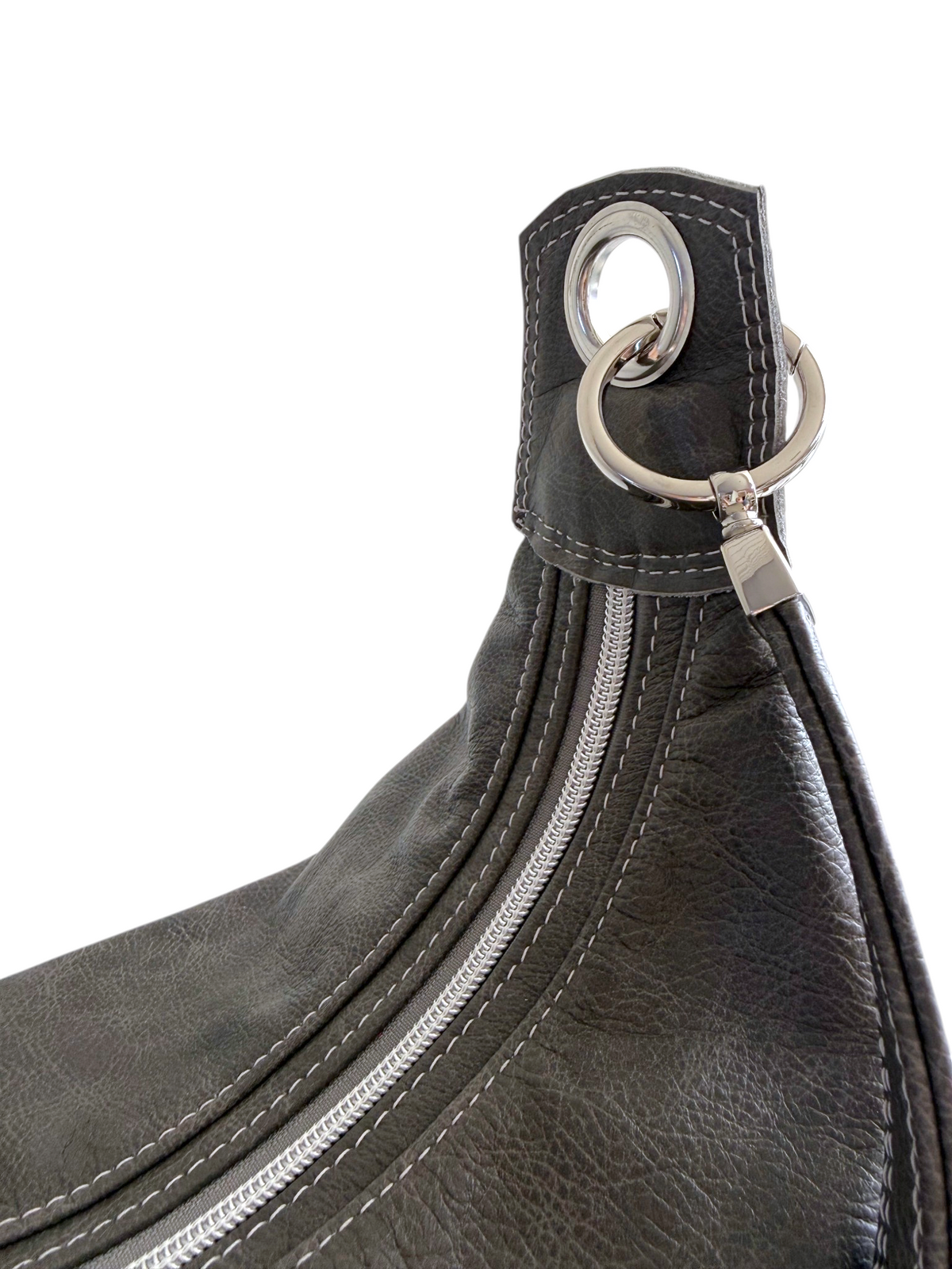 Close-up of a dark grey leather shoulder bag featuring a silver-tone metal ring and strap attachment on a white background.