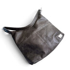 A dark grey leather shoulder bag with a slouchy hobo shape, a wide strap, and a small silver brand tag on the front, shown on a plain white background.