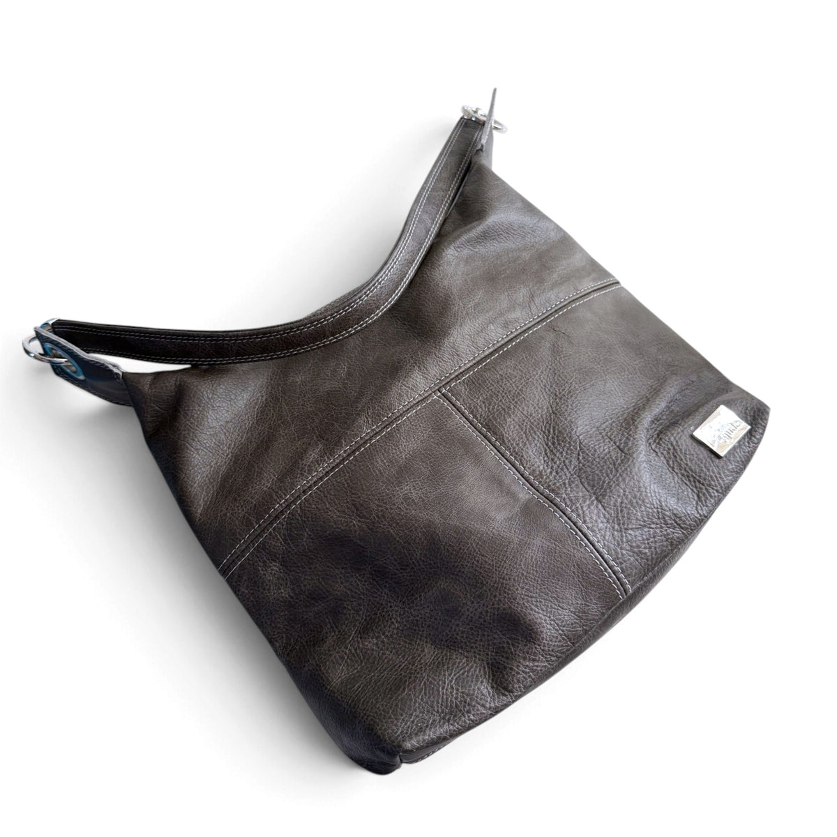 A dark grey leather shoulder bag with a slouchy hobo shape, a wide strap, and a small silver brand tag on the front, shown on a plain white background.
