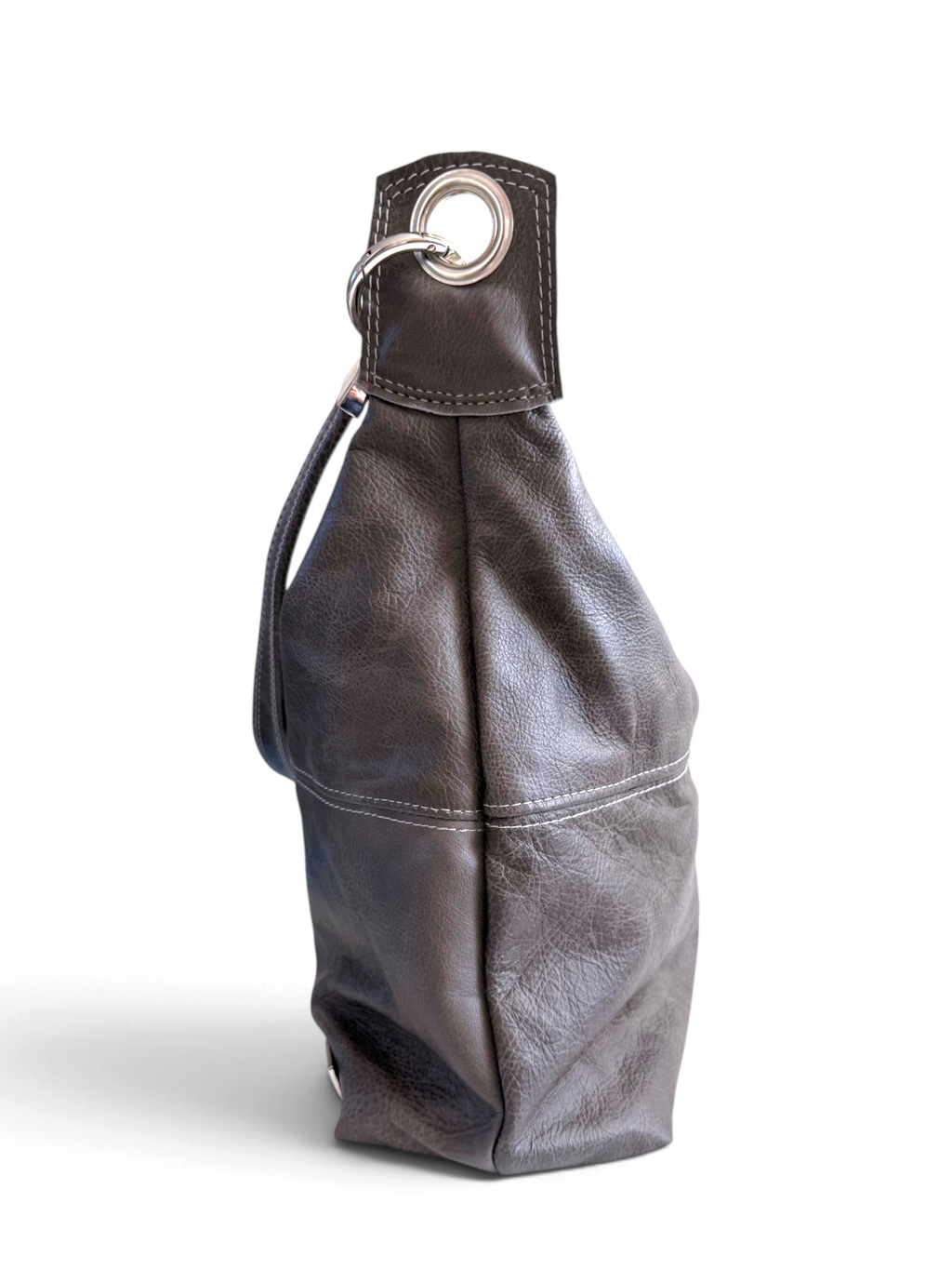 A dark grey leather shoulder bag with a slouchy silhouette, featuring a silver-tone metal grommet and ring detail on the top strap, set against a plain white background.