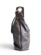 A dark grey leather shoulder bag with a slouchy silhouette, featuring a silver-tone metal grommet and ring detail on the top strap, set against a plain white background.