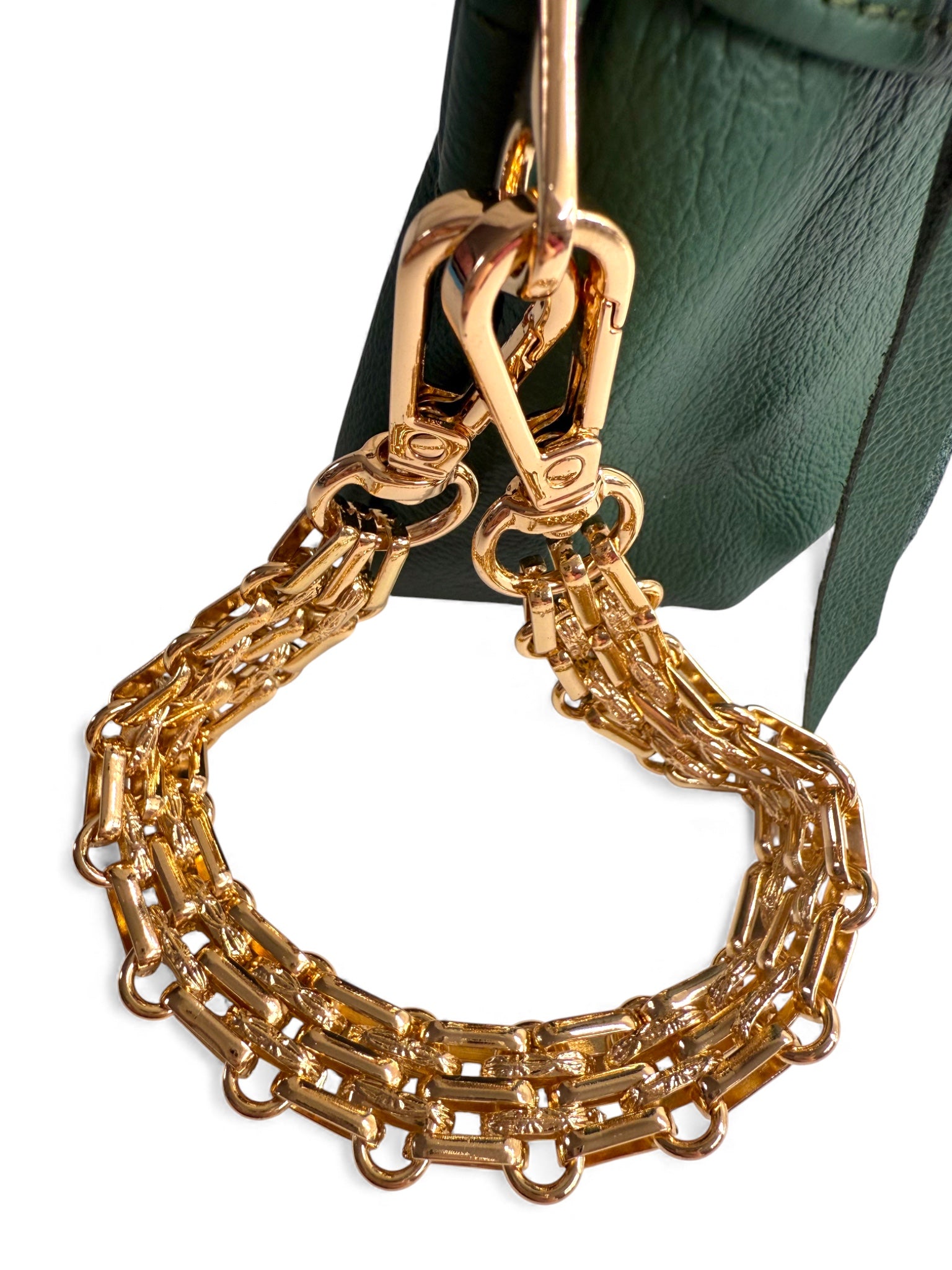 Gold chain accessory attached to a green bag. The chain is a strap that turns your clutch bag into a stylish wristlet bag.