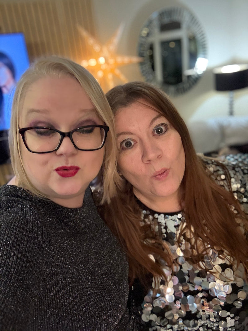 Two women posing for a selfie indoors with decorative elements in the background.