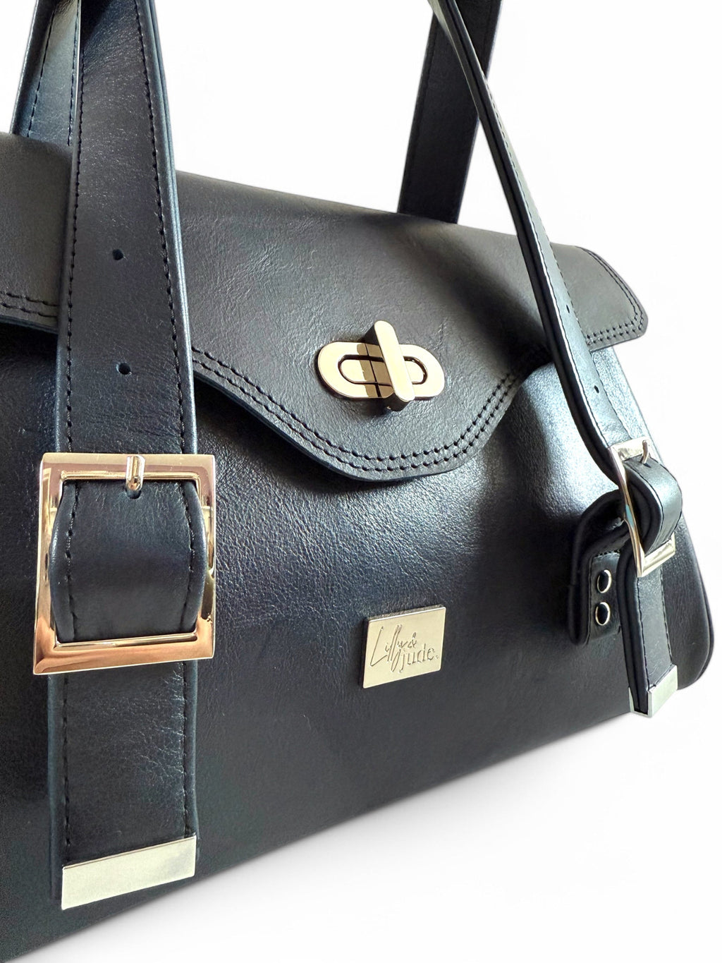 Navy leather handbag with silver buckles and turn clasp on a white background