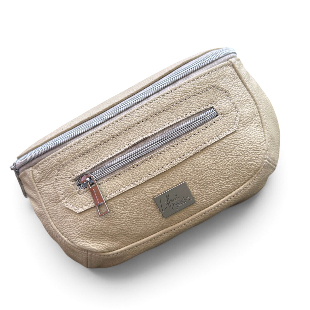 A butter yellow pebbled leather waist bag with silver zippers and a small metal brand plaque, shown on a white background.