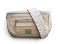 A cream coloured leather bum bag with a patterned cream and beige woven shoulder strap, featuring silver zippers and a brand label on a white background.