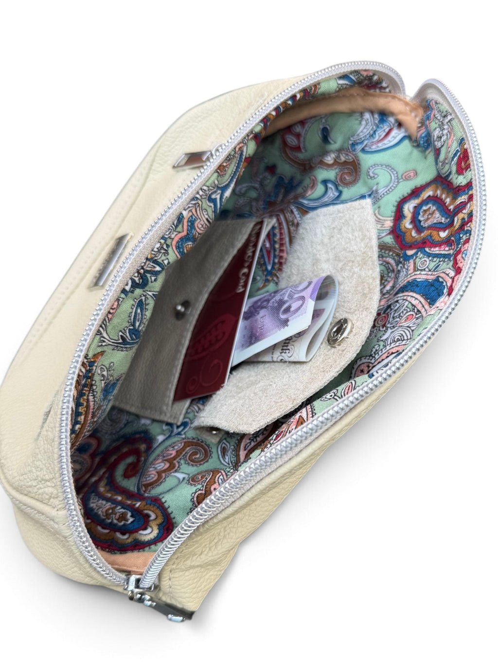 An open cream-colored leather zippered pouch with a colorful paisley-patterned interior lining, shown against a plain white background.
