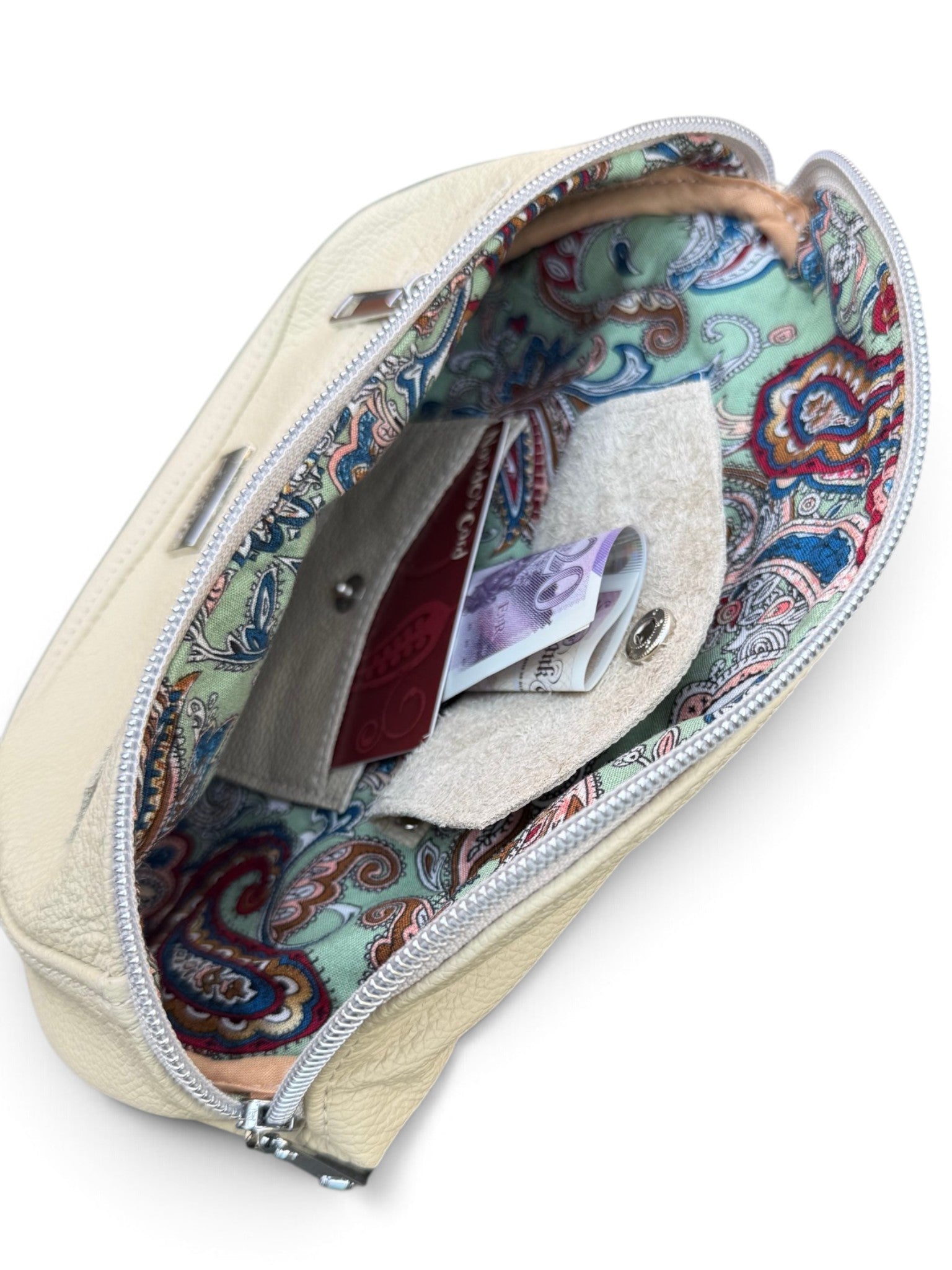 An open cream-colored leather zippered pouch with a colorful paisley-patterned interior lining, shown against a plain white background.
