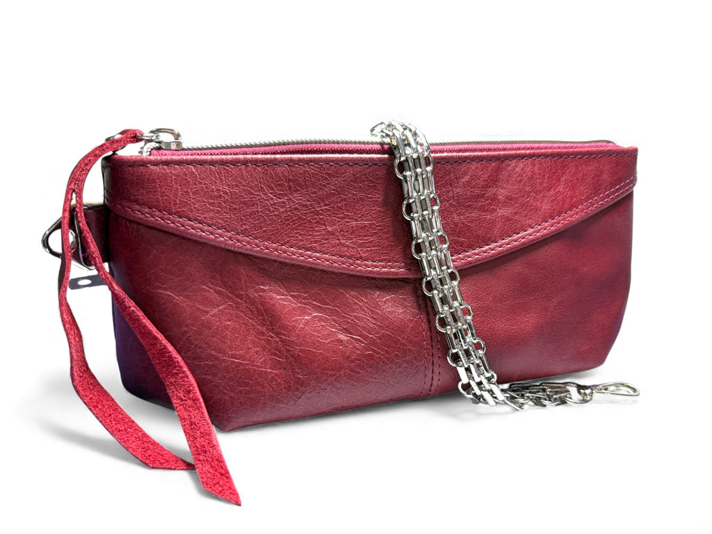 Red leather clutch bag with the multi row  silver chain strap, draped over it on a white background