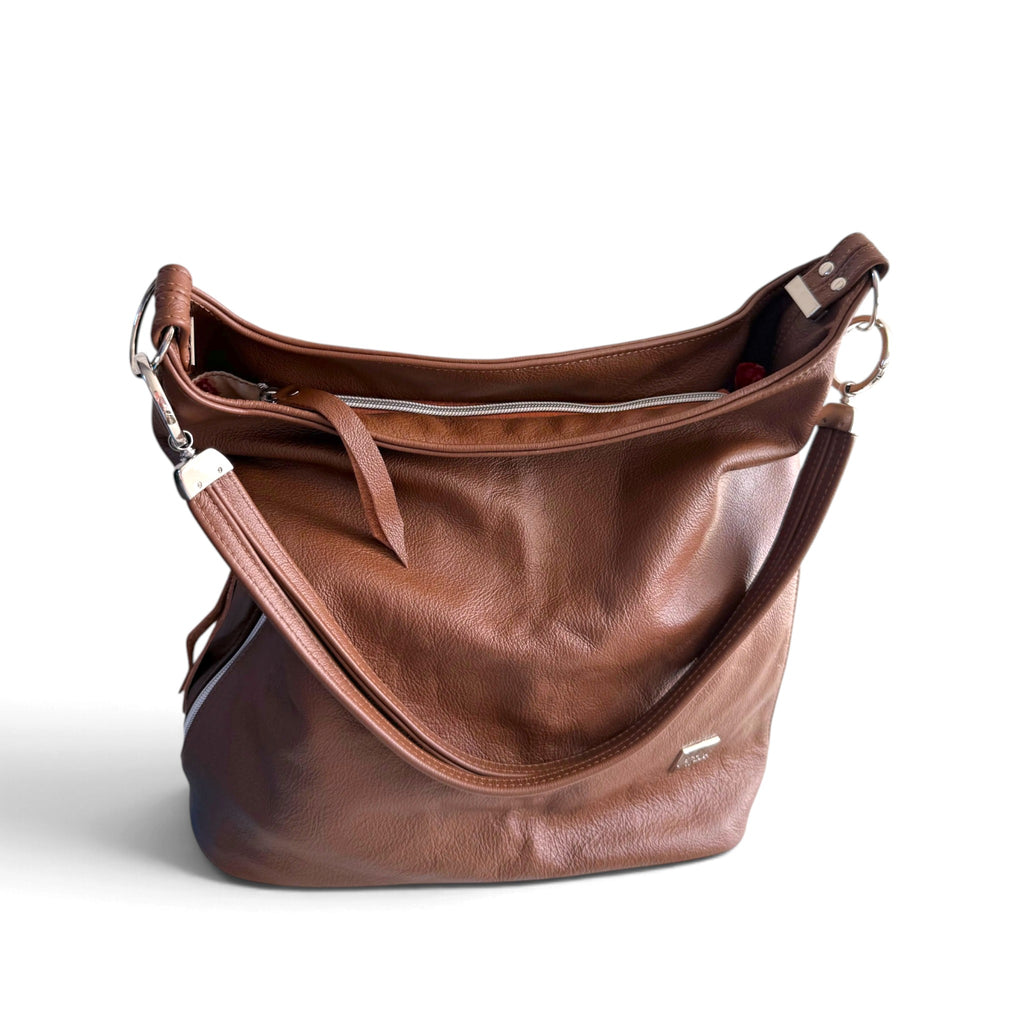 A brown leather shoulder bag with a slouchy shape, silver-tone hardware, and a matching leather strap, photographed on a clean white background.