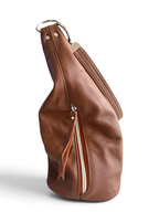 A brown pebbled leather slouchy shoulder bag shown from a side profile view, featuring a silver zipper pocket with a leather pull tab, set against a plain white background.