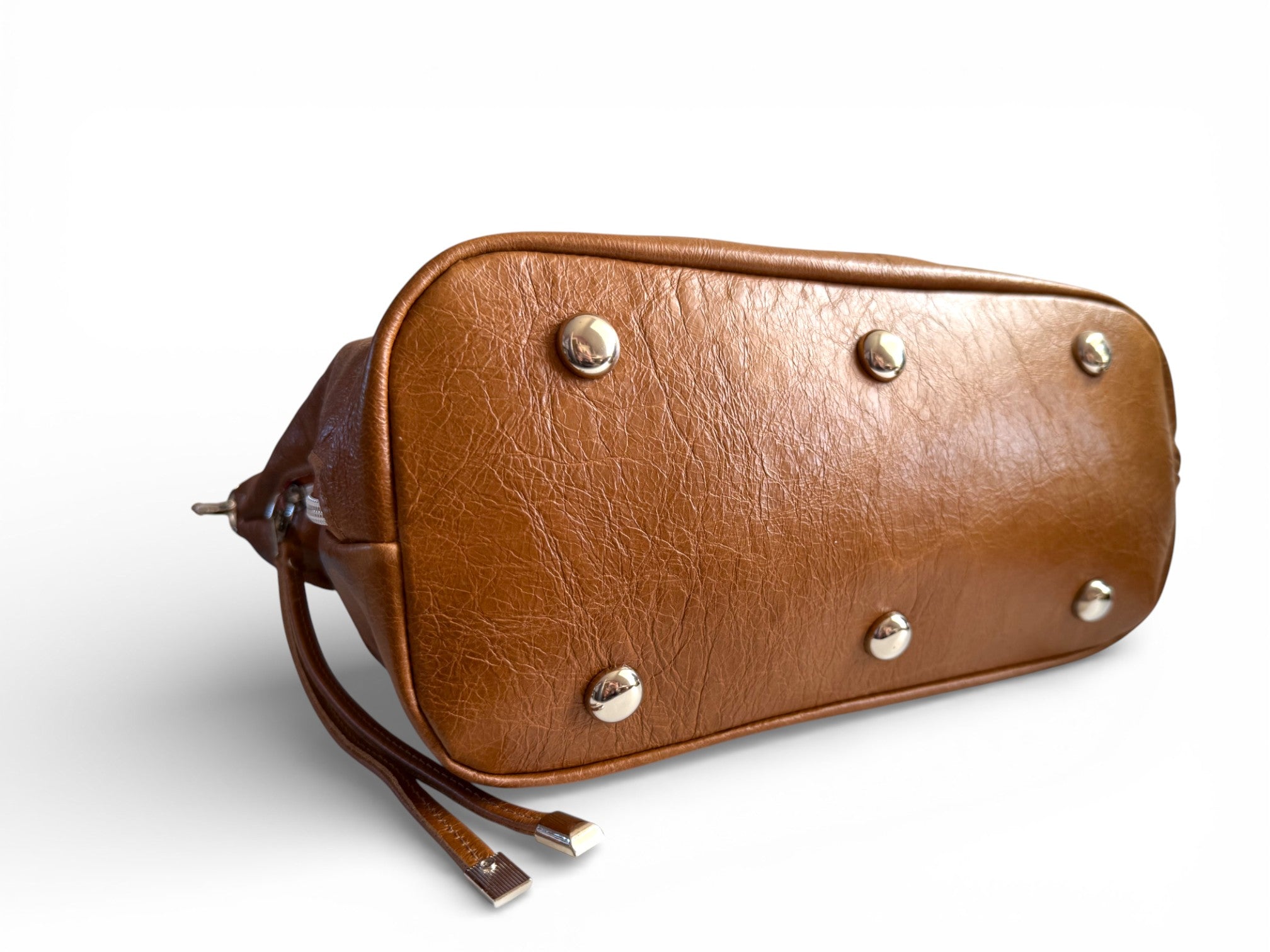View of the bottom of a Brown leather handbag with six silver studs / bag feet, on a white background