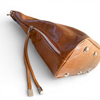 view of the bottom quarter of the Simone slouch bag by Lilly & Jude. The image shows the detailing of the side pocket, the tassels on the zipper pull and the feet on the bottom of the bag