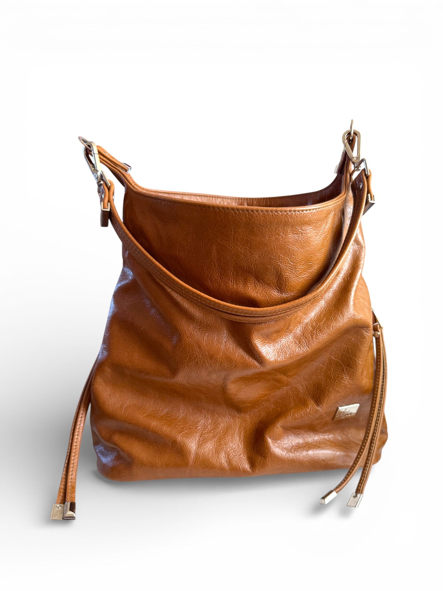 Tan, genuine leather, slouchy tote bag, with tassels and a double strand shoulder strap, on a white background.
