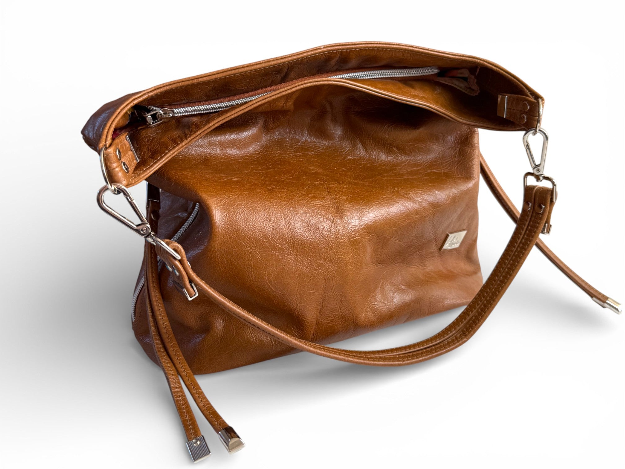 Tan brown leather slouch handbag with a strap on a white background