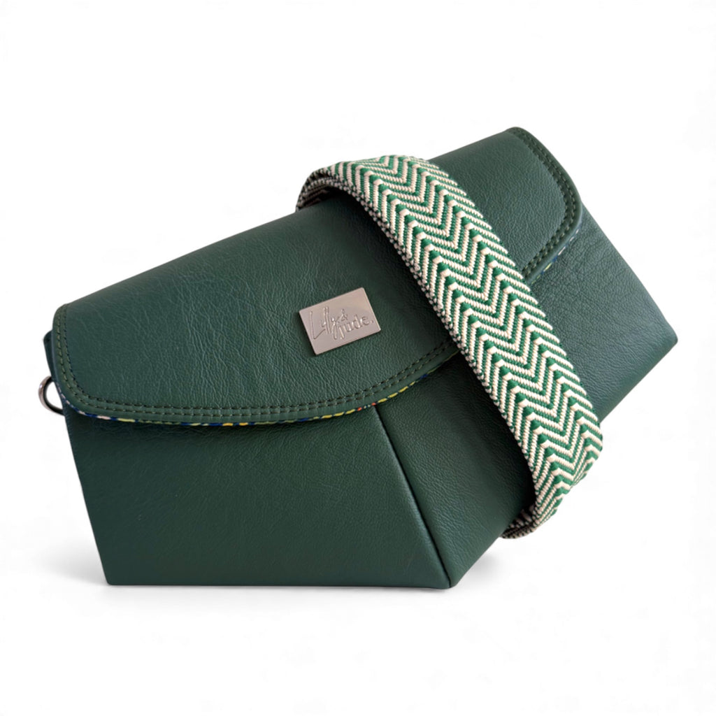 Green leather bag with a herringbone strap crossbody strap on a white background. The bag can be worn in multiple ways