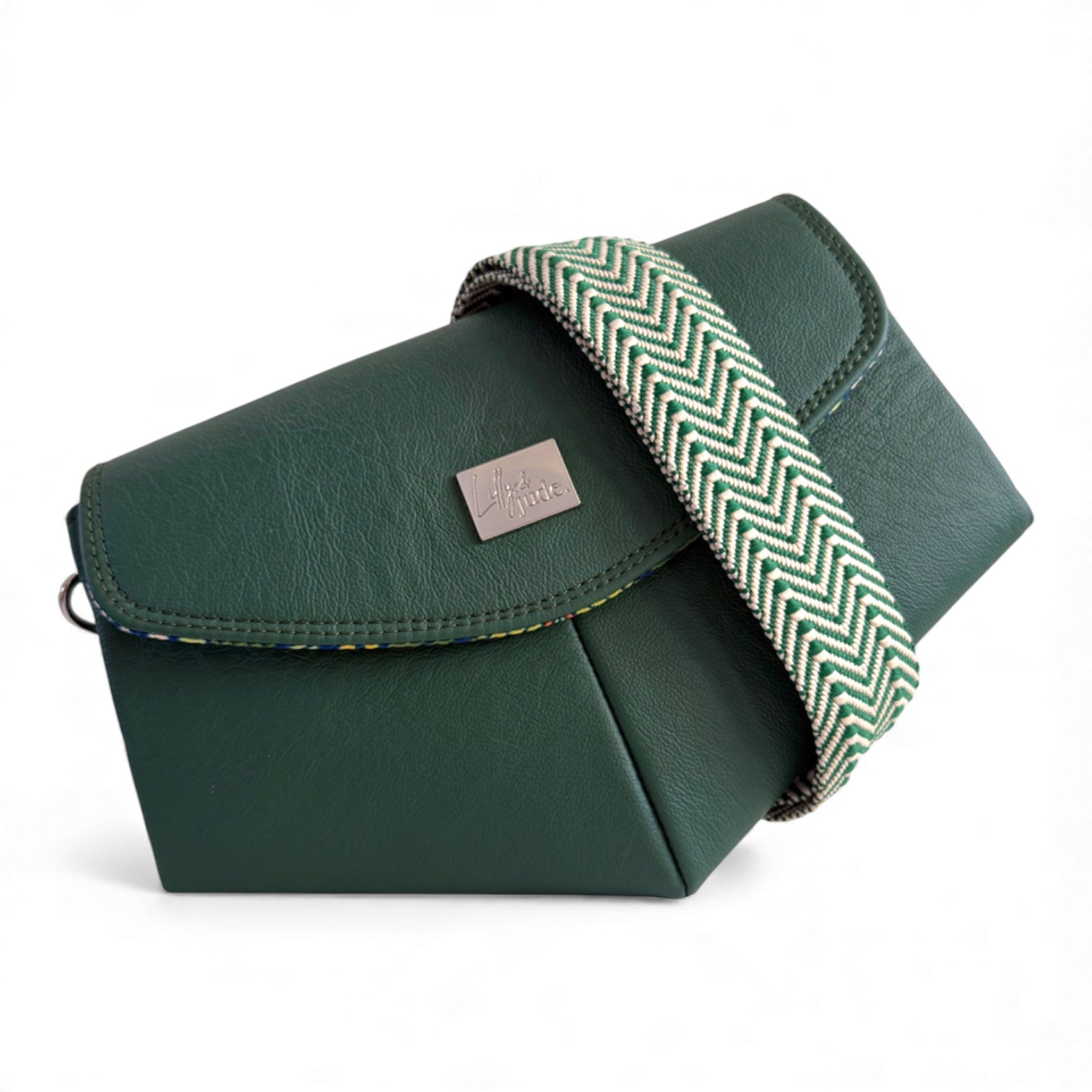 Green leather bag with a herringbone strap crossbody strap on a white background. The bag can be worn in multiple ways