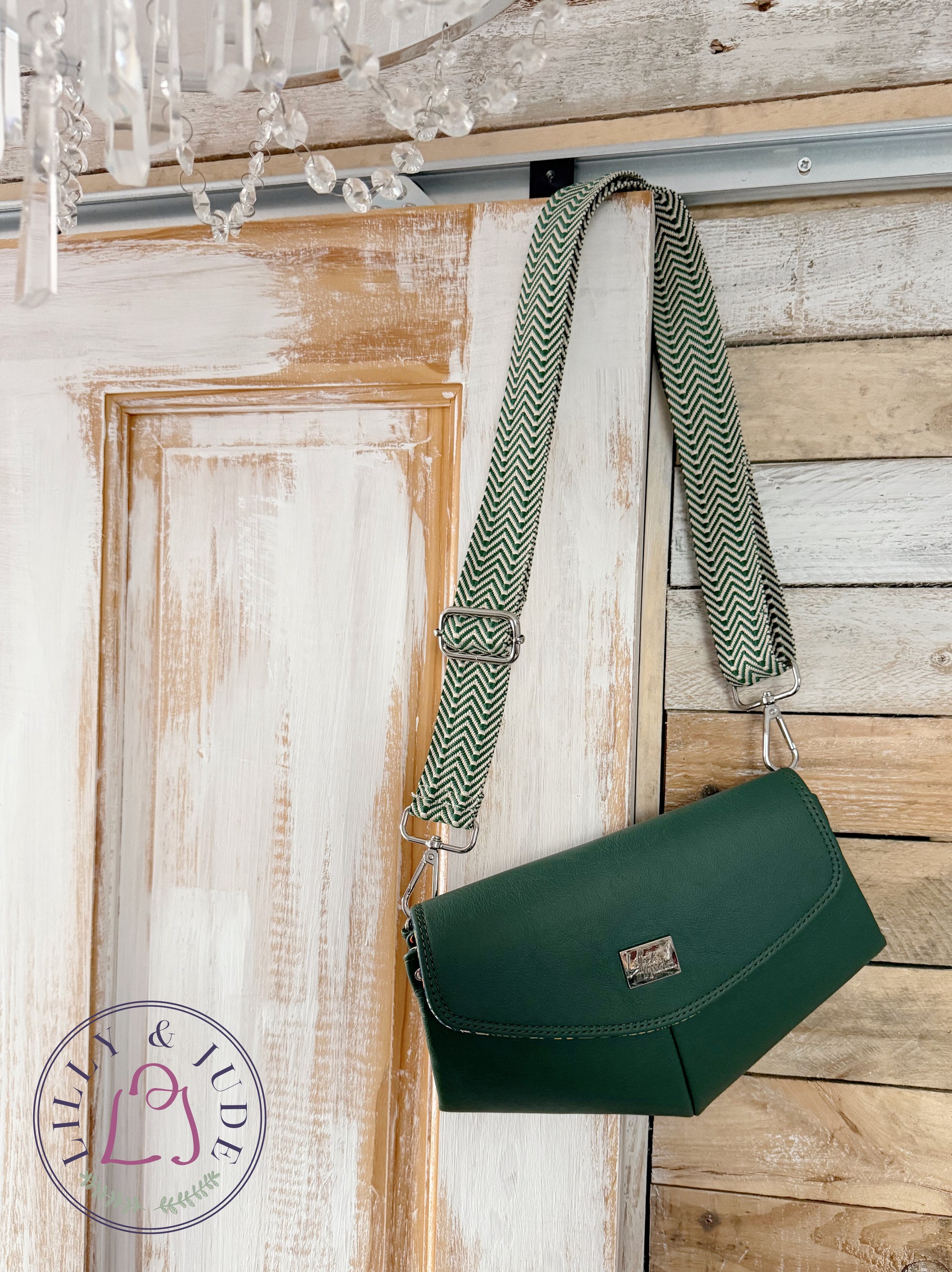 Green leather handbag with a patterned crossbody strap hanging on a wooden door