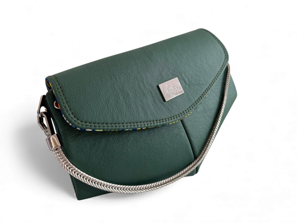 Handcrafted, dark green leather handbag with a chain detail on a white background. Handcrafted in England by Lilly & Jude