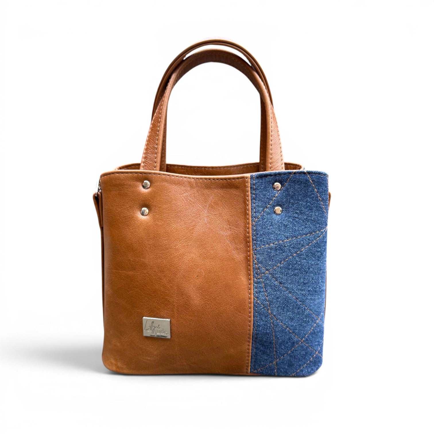Tan brown leather and blue denim tote handbag on a white background
