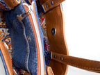 Close-up of a handbag with denim front pocket and patterned interior.