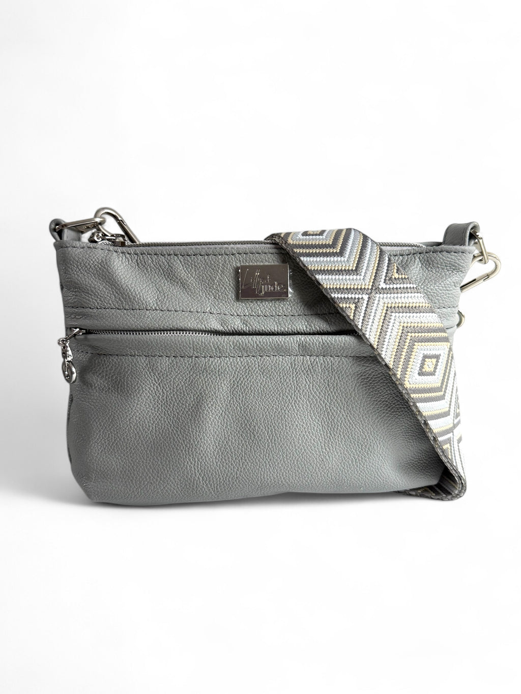 A light grey leather crossbody bag with a geometric pattern on the strap and silver hardware.