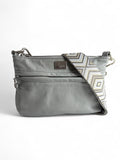 A light grey leather crossbody bag with a geometric pattern on the strap and silver hardware.