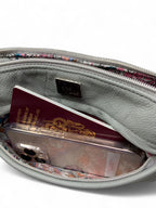 Grey rescued  leather starburn crossbody bag with a passport and phone inside the open front pocket, on a white background.