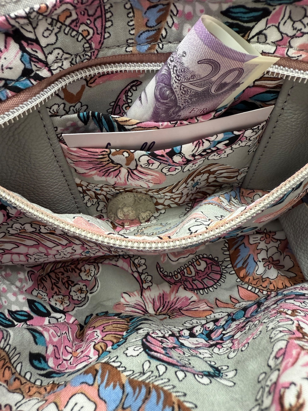 Interior view of the Starburn crossbody bag, showing the paisley patterned lining and the open zipper pocket that holds the integrated purse. Inside is a £20 note and some coins