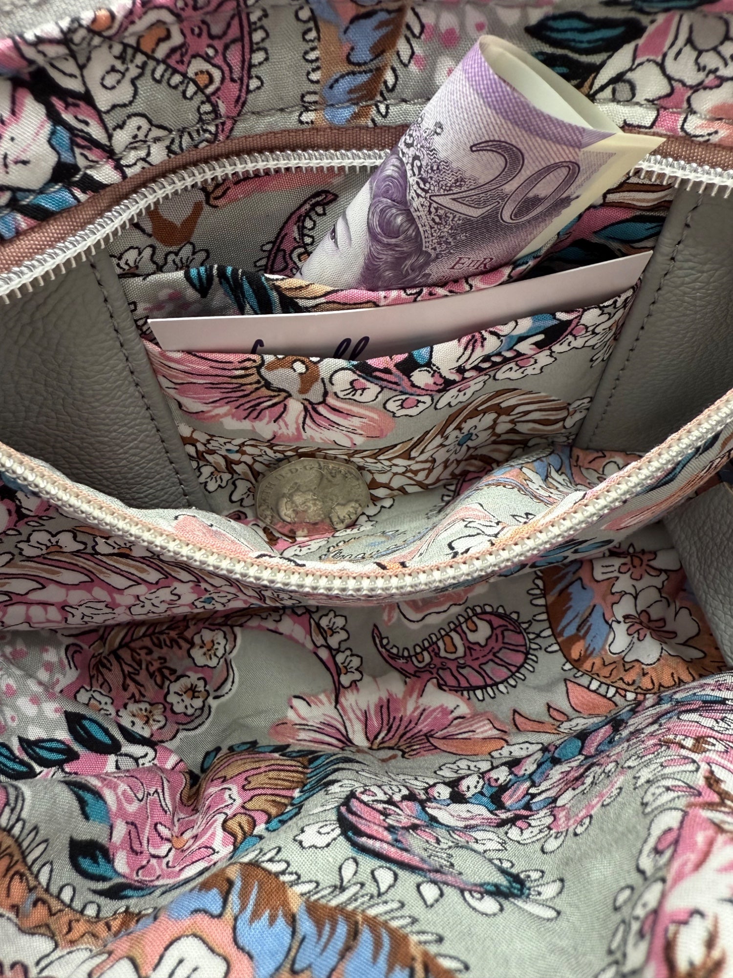 Interior view of the Starburn crossbody bag, showing the paisley patterned lining and the open zipper pocket that holds the integrated purse. Inside is a £20 note and some coins