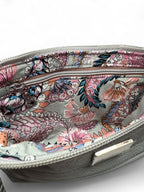 View of the inside of a light grey leather starburn, showing the floral patterned interior lining, with a zipper on a plain background